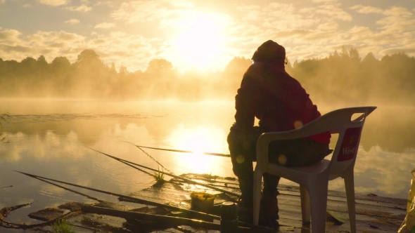 Fisherman At Sunrise Fishing On The Float Rod.