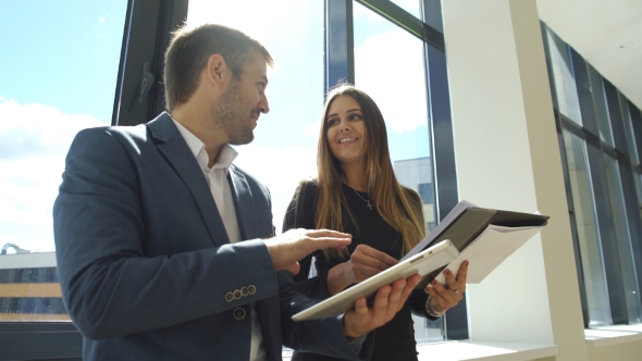 Happy Coworkers Discussing The Contract In The Office Near The Window
