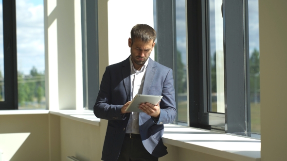 a Successful Businessman Uses Tablet And Looks Out The Window alt