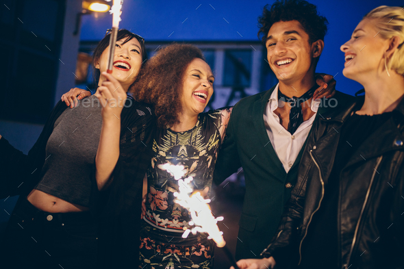 Young man and women in city at night with fireworks
