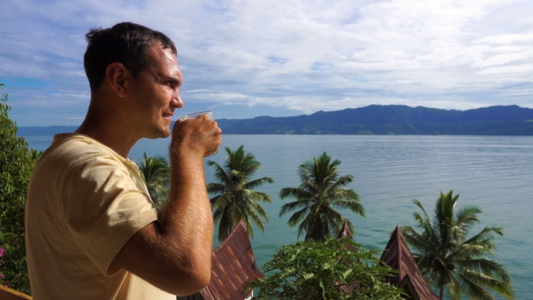 Male Traveler Drinking Coffee and Looking at Toba Lake From Samosir Island alt