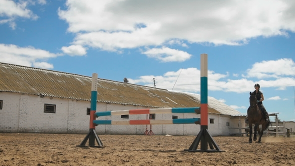 Young Woman Jumps Horse Over An Obstacle During Her Training In An Arena alt