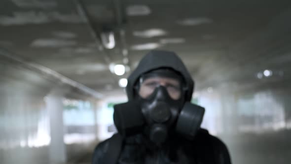 Man in Gas Mask Leather Jacket with Hood Standing at Long Tunnel Underpass