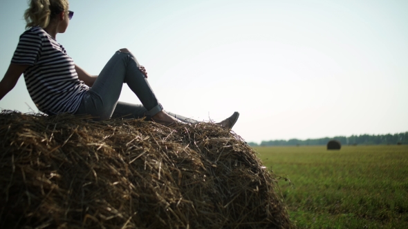 Young Stylish Girl In a Striped T-shirt Sitting On a Haystack.