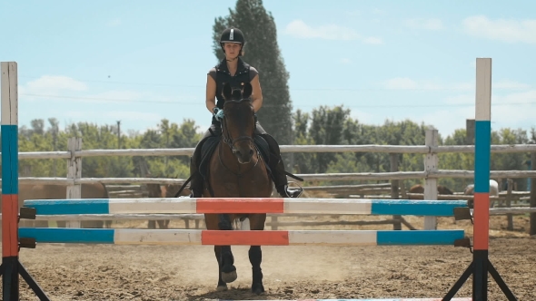 Young Woman Jumps Horse Over An Obstacle During Her Training In An Arena alt