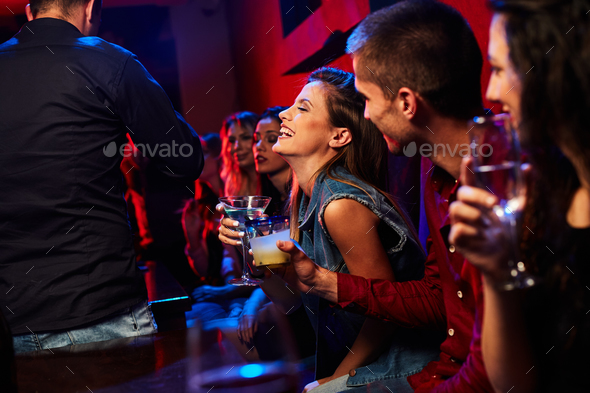 beautiful girl sitting in the club with friends and laughs