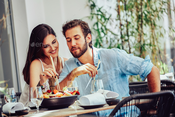Young couple sitting in the outdoor bar and eat fruit plate