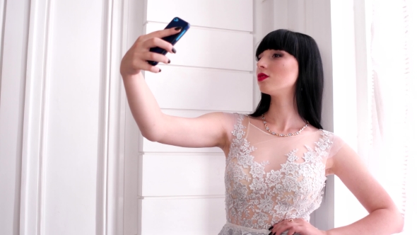 Selfie Photo At The Window, Beautiful Girl Smiling Mobile Phone With Touch Screen Makes The Picture alt