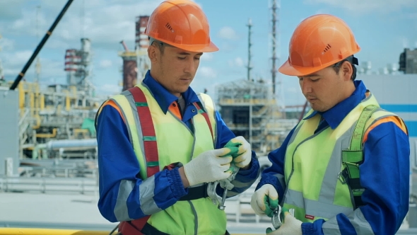 Workers In Production Plant As Team Discussing, Industrial Scene In Background alt