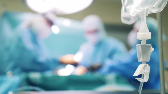 Blurred Image of Surgery Process with an IV Bag Hanging Nearby alt