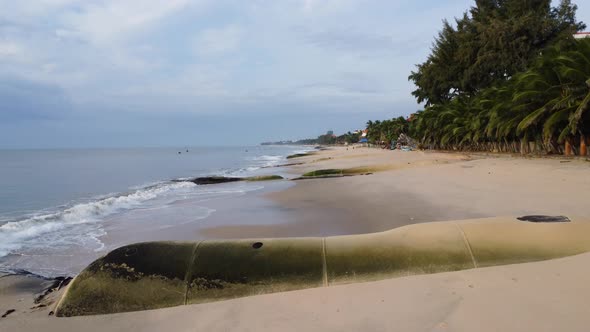 Aerial, low flyover tropical beach with giant aqua bags on shore to prevent erosion caused by rising alt