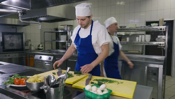 Overworked Caucasian Man in Apron and Cook Hat Rubbing Forehead Looking Away with Colleague Passing alt