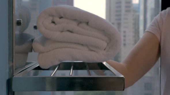 Housekeeper Placing Bath Towels In Hotel Bathroom alt