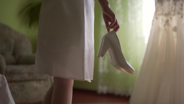 Bride With Wedding Shoes In Hes Hands. At The Bottom Of It Says With Small Diamonds