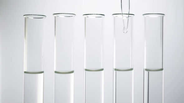 A Pipette Drips Transparent Water Into a Test Tubes