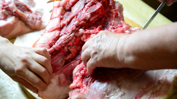 Two Women Cut a Large Piece Of Pork