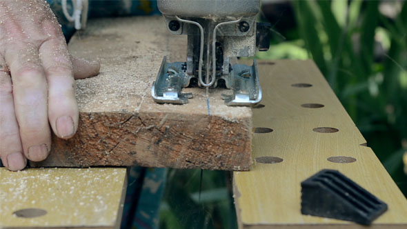 Man Sawn a Wooden Board with an Electric Jigsaw. alt