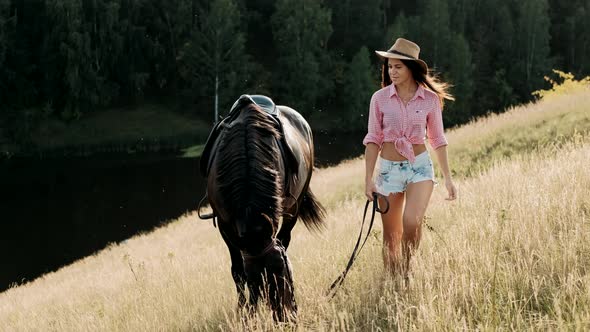 Beautiful Woman in Hat Leads a Horse. Young Girl Spending Outdoor Leisure Activity, Enjoying alt