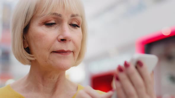 Closeup Focused Serious Caucasian Elderly Woman Holding Smartphone Looking at Phone Screen Typing alt
