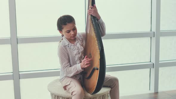 A Teenage Girl Bandura Player Performs a Piece of Music on the Bandura alt