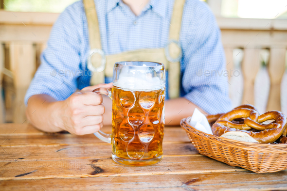 Man in traditional bavarian clothes with beer and pretzels