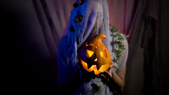 Halloween Witch With a Magic Pumpkin In a Dark Room alt