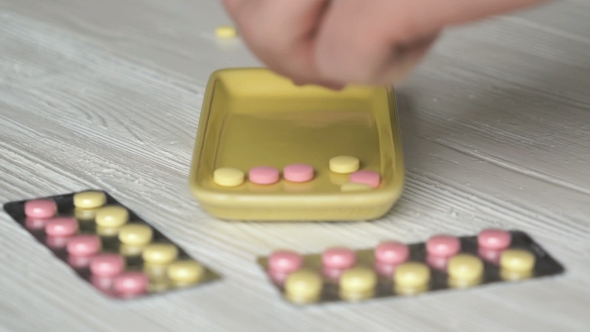 Hand Collects The Tablets In a Yellow Container alt