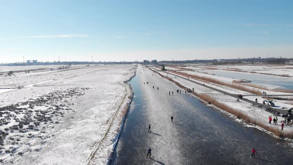 People ice skating on frozen canal, iconic Netherlands winter scene, aerial view alt
