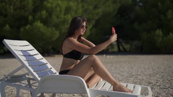 Pretty Girl Making Selfie While Listening to Music on the Beach