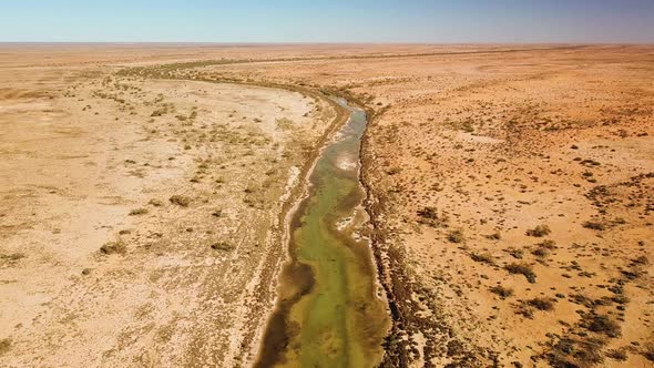 High flying drone footage of spring fed river winding through arid Australian desert region. alt