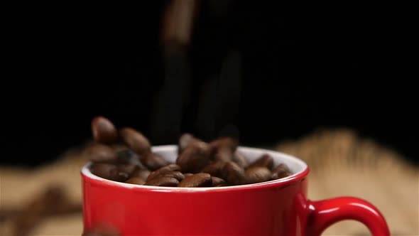 Coffee Beans Falling Into Red Small Cup. Slow Motion alt
