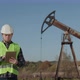 Engineer Near an Oil Pump Holding Digital Tablet and Looking at Camera - VideoHive Item for Sale