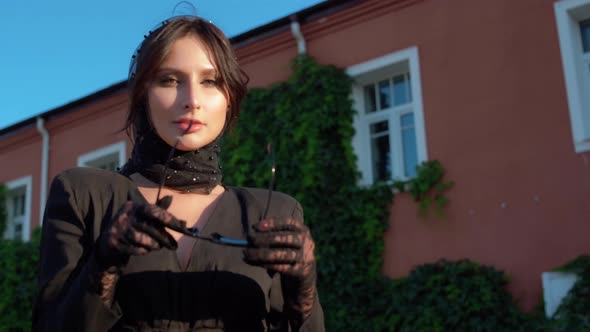 Pretty European Girl in Black Dress and Headscarf Walks Through Streets of the City alt