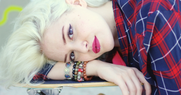 Hipster Young Woman Lying On a Skate Board alt