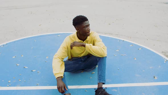 Portrait of a young man sitting on a playground alt