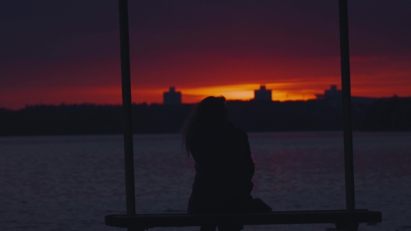 Silhouette Of a Girl Sitting On a Bench And Admire The Sunset.