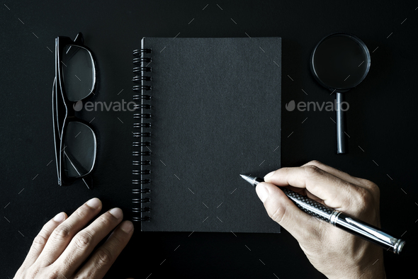 Black notebook with copyspace on black background and hand writing