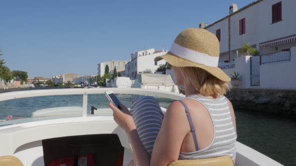 Woman Tourist Sailing On a Small Boat On The Canal. Use Mobile Phones. Empuriabrava, Spain alt