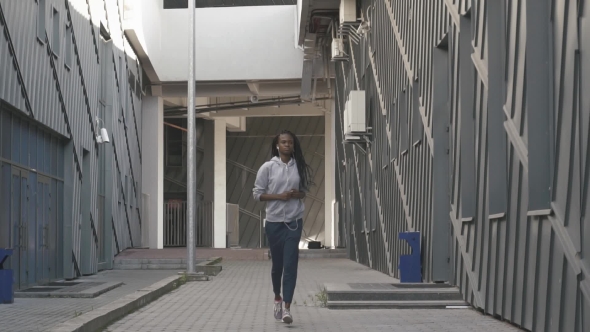 Young Woman Running And Listening To Music In An Urban Street