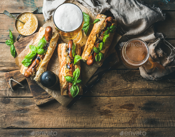 Glasses of wheat unfiltered beer and homemade grilled sausage dogs - Stock Photo - Images