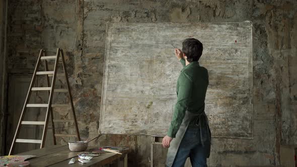 Talented Male Artist Working on an Abstract Painting Applies Light Strokes with a Brush alt