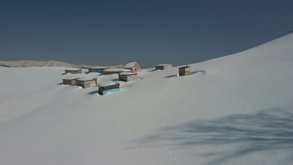 Aerial View of an Alpine Settlement on a Background of Snowcovered Winter Mountains