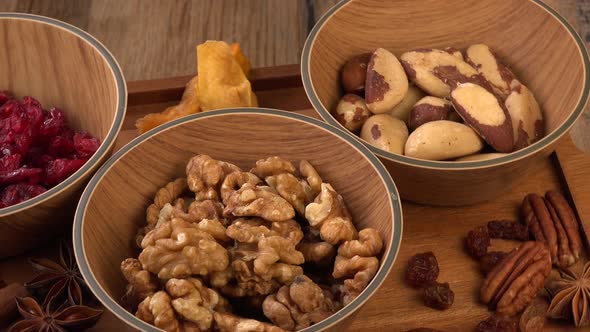 Mixed nuts and dried fruits in wooden bowl on wood background