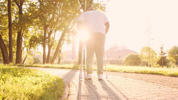 Disabled African-American man is walking with a walker. Patient in the park. alt