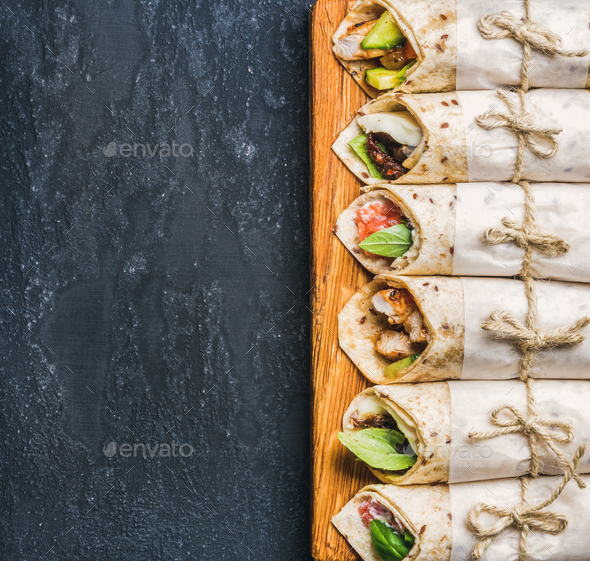 Tortilla wraps with various fillings on dark grey concrete background - Stock Photo - Images