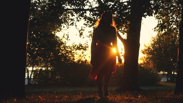 Joyful Girl Runs Through the Sun in Autumn Park in During Sunset