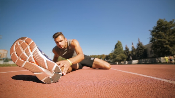 Male Athlet Stretches His Leg At The Stadium alt