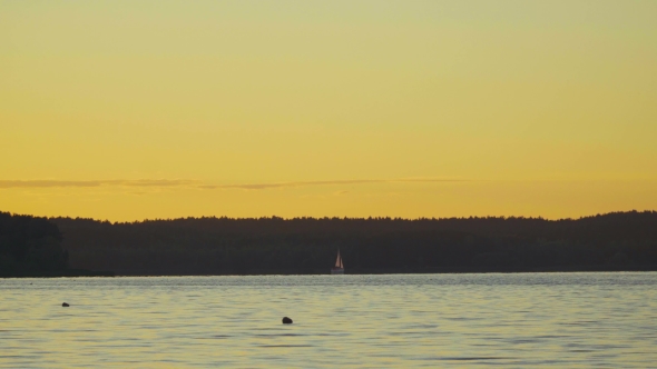 A Small Sailing Boat On The Water At Sunset