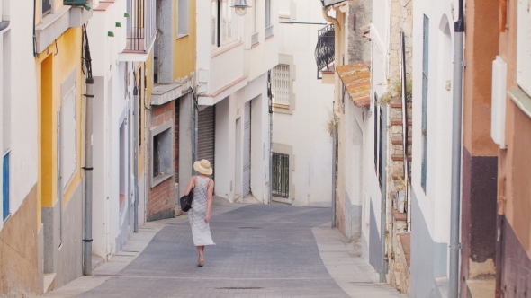 Woman Tourist Goes Down the Narrow Streets of the Old Mediterranean City alt