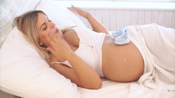 Pregnant Woman Playing With Baby Booties On Belly